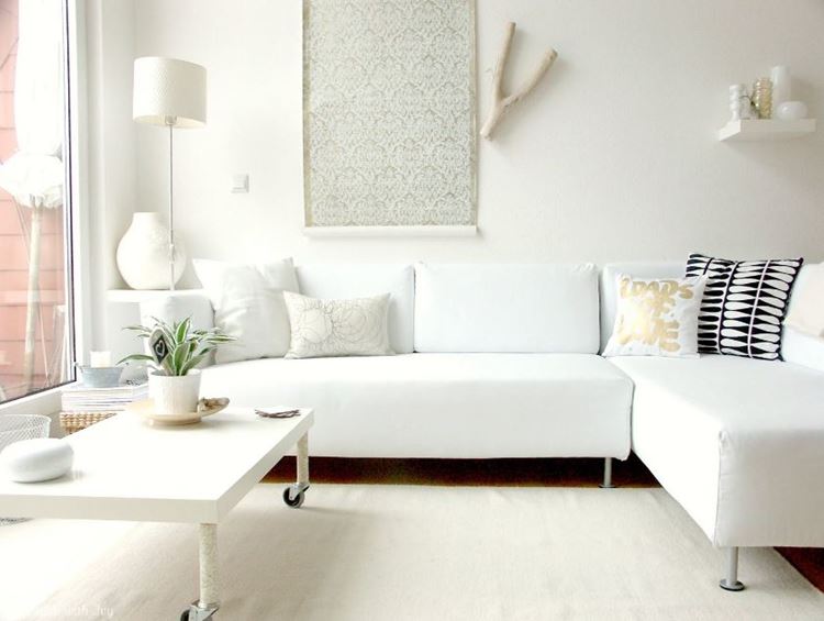 Белый диван в интерьере: монохромная белая комната с угловым диваном, кофейным столиком и аксессуарами