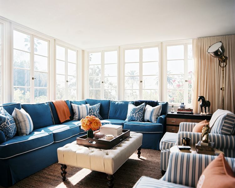 Голубой диван в интерьере: большой угловой диван с подушками в светлой комнате с большими окнами