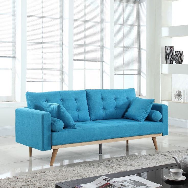 Голубой диван в интерьере: диван с подушками и на деревянных ножках в гостиной с белыми стенами и серым ковром 