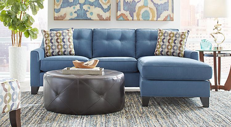 Голубой диван в интерьере: трёхместный диван  с подушками с принтом и кожаным пуфом-столиком