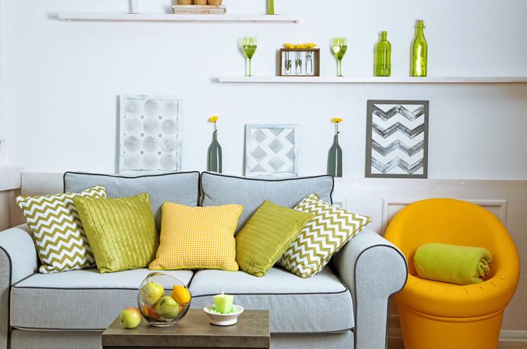 Голубой диван в интерьере: двухместный мягкий диван с яркими жёлтыми и зелёными подушками 