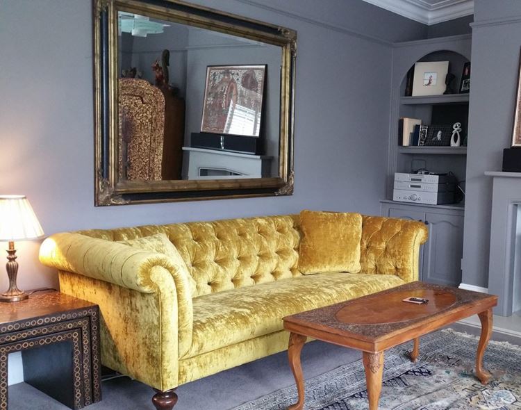 Жёлтый диван в интерьере: гостиная со старинным вельветовым жёлтым диваном и деревянным столиком