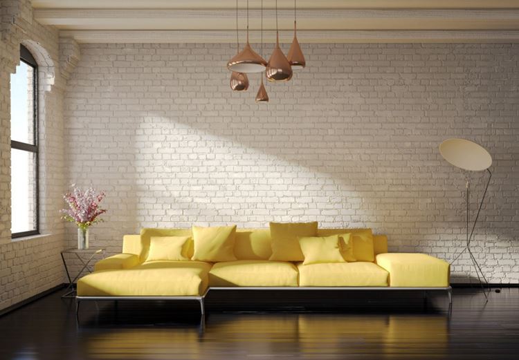 Жёлтый диван в интерьере: гостиная в стиле лофт с кирпичной стеной и жёлтым угловым диваном с подушками
