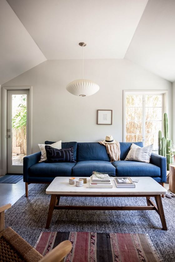Джинсовый диван - трехместный с подушками в гостиной с белыми стенами